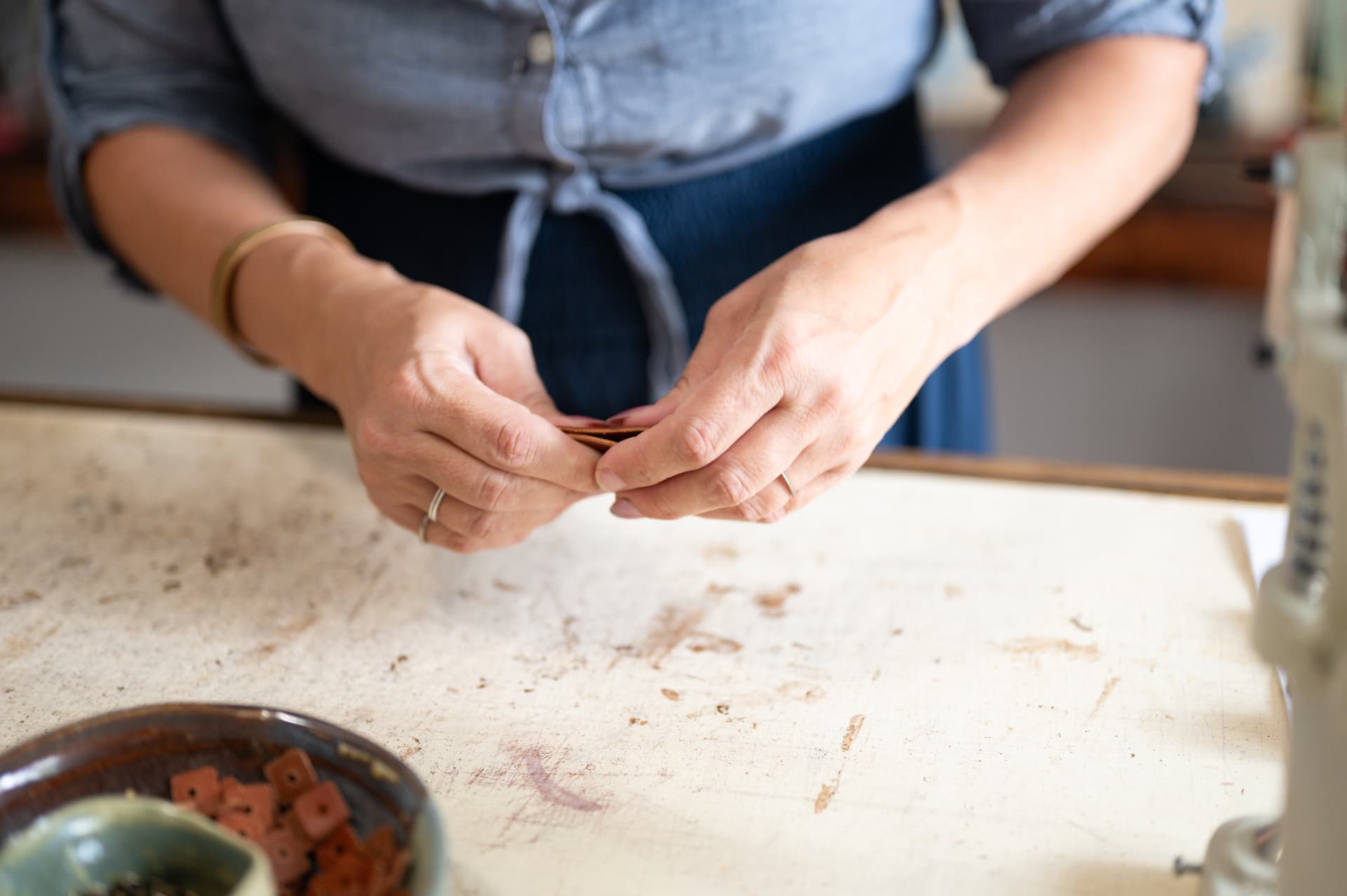 Hands finishing leather at the bench