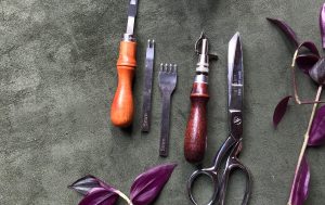 Leatherworking tools on a green suede workbench