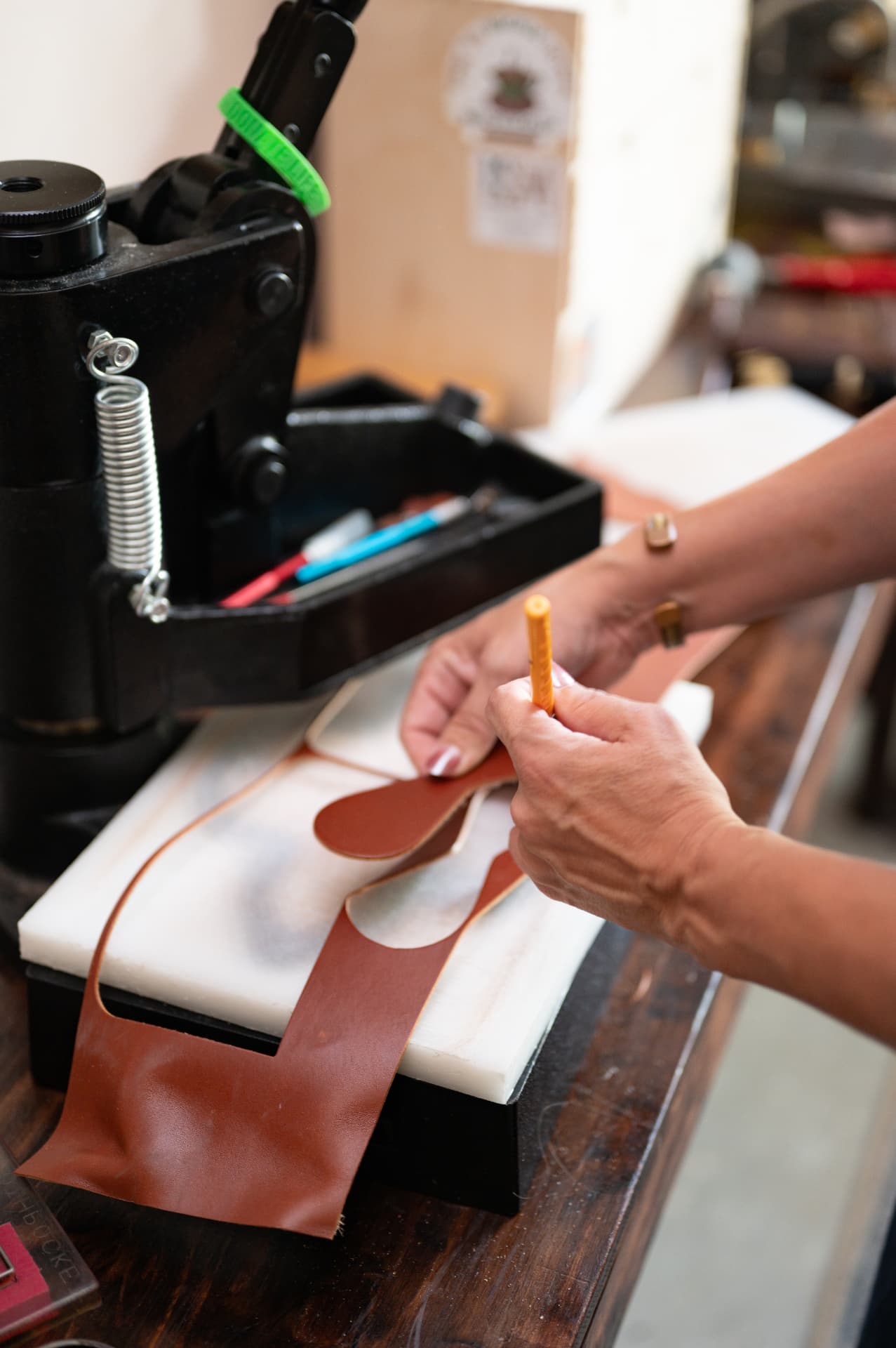 Hands with cut leather pieces on the workbench