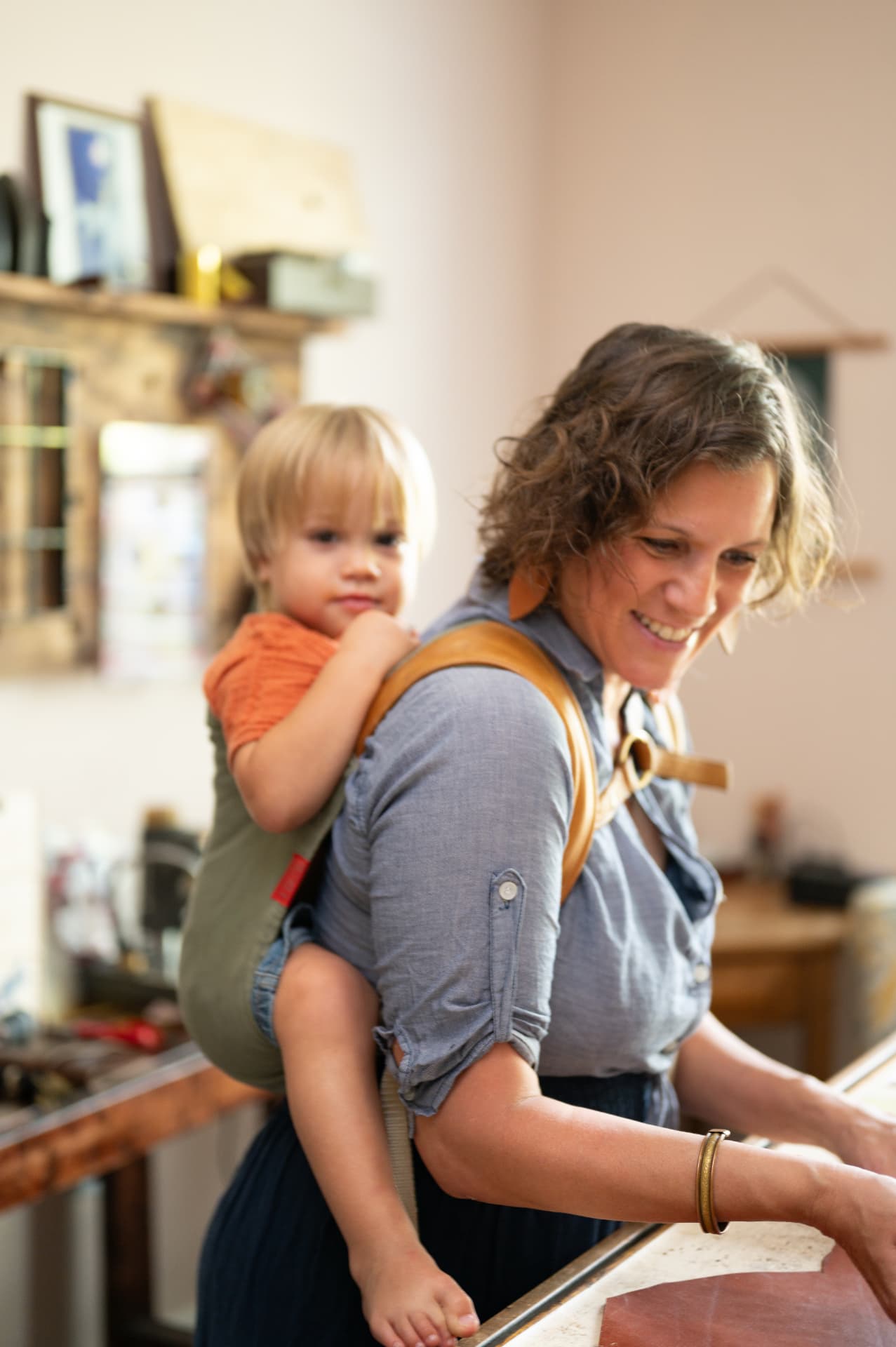 Sarah working at the bench with a baby on her back